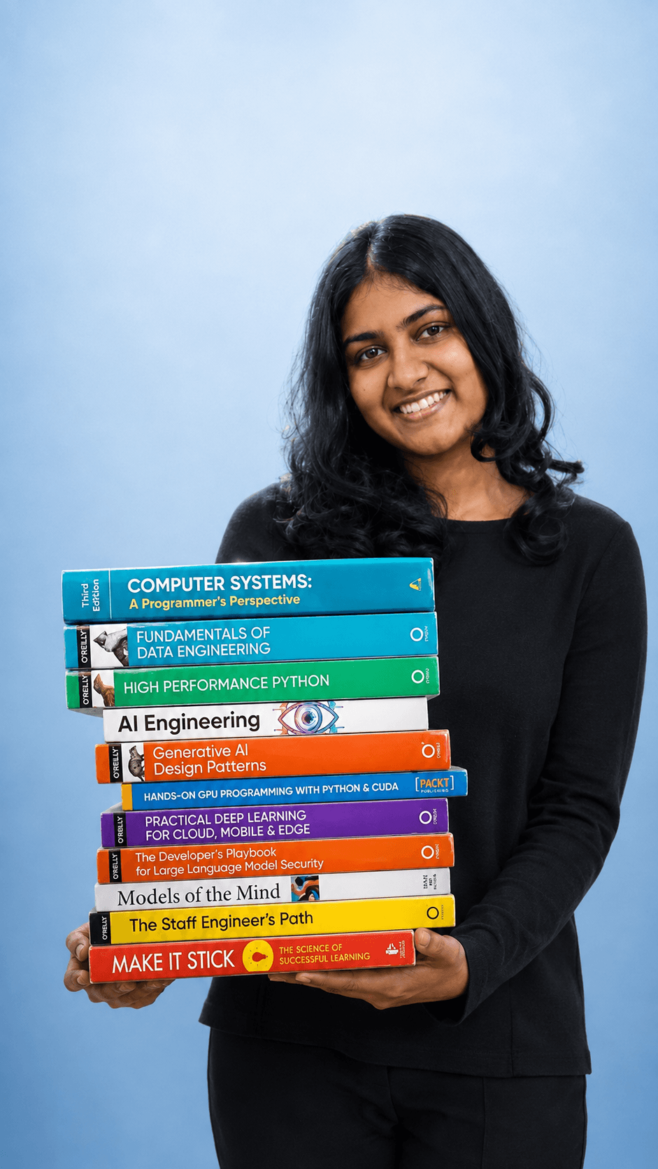 Upeksha smiling while holding a stack of programming and AI books